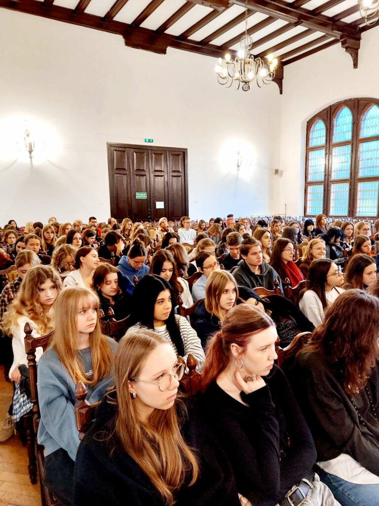 Zdjęcie przedstawia grupę uczniów słuchających psychologów z Centrum Psychiatrii Anima w Olsztynie. Na twarzach uczestników widać zainteresowanie i zaangażowanie.